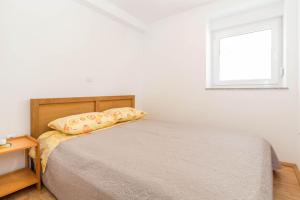 biała sypialnia z łóżkiem i oknem w obiekcie Apartment MiMa w Medulinie