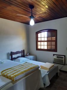 a bedroom with two beds and a window and a fan at Gil's suites in Paraty