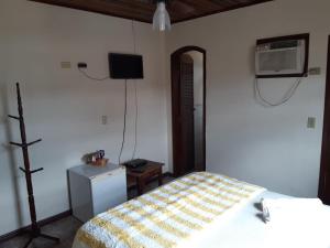 a bedroom with a bed and a tv on the wall at Gil's suites in Paraty