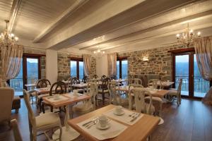 un restaurante con mesas y sillas de madera y ventanas en Thisoa Hotel, en Karkaloú