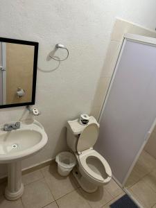 Un baño con inodoro, lavabo y espejo. en Bungalow Clavel Barra la Saladita, en La Salada