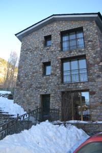 un edificio de piedra con ventanas y nieve delante de él en Casa Nova Regi en Soldeu