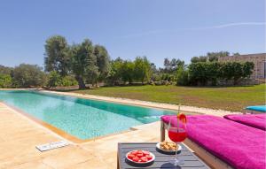 a table with a glass of wine next to a pool at 2 Bedroom Cozy Home In Ostuni in Ostuni