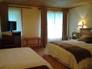 um quarto de hotel com duas camas e uma televisão em Espacio y Tiempo Hotel de Montaña em La Junta