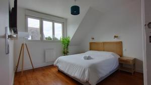 a white bedroom with a bed and a window at Charmante maison rénovée au bord de mer in Locmiquélic
