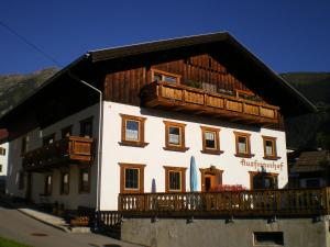 un grand bâtiment blanc avec un toit en bois dans l'établissement Ausfernerhof, à Berwang