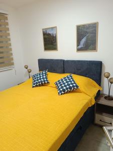 1 dormitorio con 1 cama amarilla y 2 almohadas en Apartman Pogled, en Veliko Gradiste