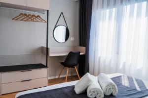 a bedroom with a bed with a mirror and a chair at Nani Apartment in Prizren
