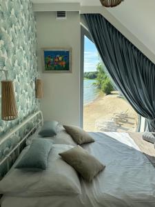 a large bed with pillows in a bedroom with a window at MaVe Park in Chmielno