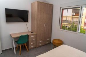 a bedroom with a desk and a cabinet with a television at Céntrico y luminoso in Huelva +2 photos