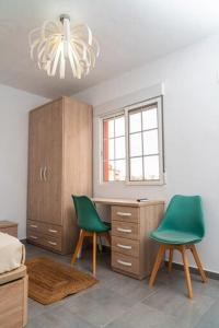 a bedroom with a desk and two green chairs at Céntrico y luminoso in Huelva