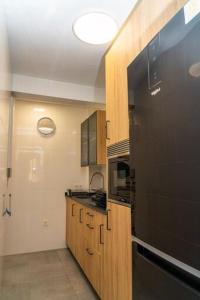 a kitchen with wooden cabinets and a black refrigerator at Céntrico y luminoso in Huelva