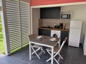 eine Küche mit Tisch und Stühlen und einem Kühlschrank in der Unterkunft Kaz et Palmiers in Saint-François + 16 Fotos
