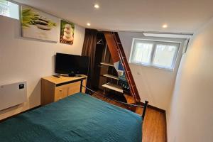 a small bedroom with a bed and a television at Petite maison avec terrasse in Bezons