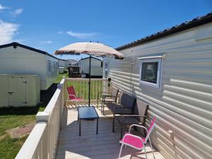 a deck with chairs and an umbrella next to a building at 26 Round Piece Lane in Selsey