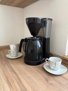 a coffee maker and two cups on a table at Blick zur Bergkirche in Weikersheim +4 photos