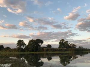 een rivier met bomen en een bewolkte lucht bij The Reserve in Harare