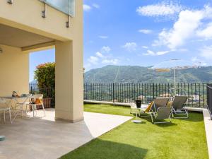 a patio with chairs and an umbrella and grass at Serenity with swimming pool and parking in Alassio in Alassio