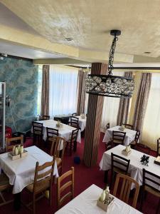 a restaurant with white tables and chairs and a chandelier at BLIM Restaurant Cazare Sound of Nature in Baia de Fier +47 photos