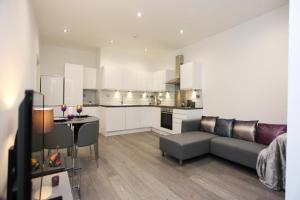 a living room and kitchen with a couch and a table at Silchester court in Luton
