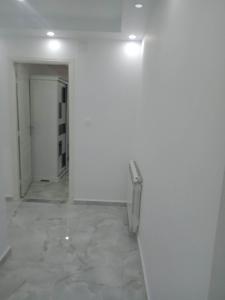 Habitación con pared blanca y silla en Bel Appartement meublé à Bordj El-Kiffane, en Stamboul