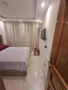 Un pequeño dormitorio con una cama y un televisor. en شارع سوريا, en Alejandría