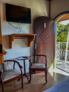 Cette chambre comprend une chaise, une table et une télévision. dans l'établissement Pousada Venezia, à Santo Antônio do Pinhal