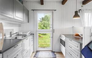a kitchen with white cabinets and a door with a window at Amazing Home In Stege With Kitchen in Stege