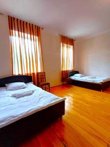 Dos camas en una habitación con suelo de madera y ventanas. en Guest house Matsantsara, en Telavi