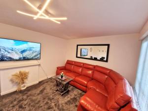 a living room with a red couch and a tv at Charming 4 bedroom house in Nottingham -Entire House in Stapleford