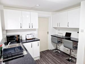 a kitchen with white cabinets and a desk with a laptop at Charming 4 bedroom house in Nottingham -Entire House in Stapleford