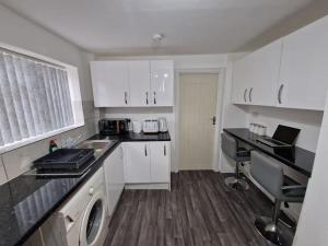 a kitchen with white cabinets and a washing machine in it at Charming 4 bedroom house in Nottingham -Entire House in Stapleford +43 photos