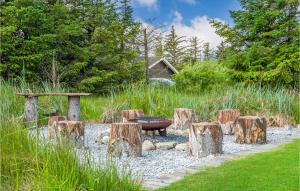 a garden with a wooden table and tree stump logs at Holiday Home Jægerens Vej in Blokhus