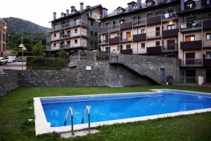 a swimming pool in front of a large building at Apartament Cal Cinto in Sort