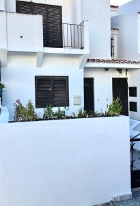 una casa bianca con porte e finestre nere di A moins de 1km de la plage maison AVEC EXTERIEUR 6 pers a Monte Gordo