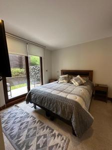 a bedroom with a large bed and a large window at DEPTO PARQUE PINARES FRENTE AL LAGO, PRIMERA LINEA, NUEVO in Pucón