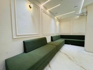 a green couch in a room with white walls at Hotel Suryodaya in Ujjain +13 photos