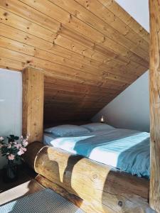 una cama en una habitación con techo de madera en Wild Cottage, en Poiana Mărului
