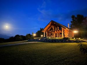 Una cabaña de troncos de noche con la luna en Wild Cottage, en Poiana Mărului
