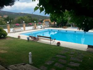 a large blue swimming pool with two benches in a yard at Hotel Segle XX in Tremp