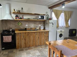 una cucina con lavandino, frigorifero e tavolo di Jireh a Esquel Altre 7 foto