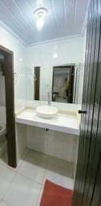 une salle de bain blanche avec un lavabo et un miroir dans l'établissement Casa com Piscina, Vista e Acesso ao Mar, à Angra dos Reis