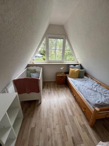 1 dormitorio en el ático con cama y ventana en Ferienhaus Teetied, en Südbrookmerland
