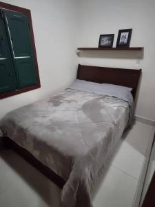 Bett in einem weißen Zimmer mit grüner Tür in der Unterkunft Casa do Cristiano no bairro Rosário in Ouro Preto