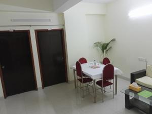 a dining room with a white table and red chairs at Rose Garden Guest House in Khulna