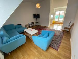 a living room with blue couches and a table at Luxury Penthouse near Metro, Train Station and 15 mins Center in Vienna
