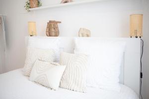a white bedroom with white pillows on a bed at 2 Pièces Cosy - Mairie Des Lilas in Les Lilas
