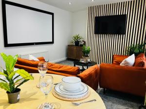a living room with orange couches and a tv at Modern two bed apartment in Hull