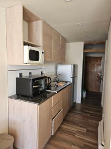 a small kitchen with a microwave and a refrigerator at Departamento dentro del centro de sky Valle de Las Leñas, Edificio Esparta in Las Lenas
