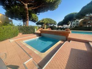 a swimming pool in a yard with trees and a building at Location Cap d'Agde Aurélie in Cap d'Agde